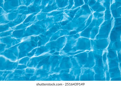 Close-up view of rippling blue water with sunlight reflections on a swimming pool surface, creating a calming abstract pattern. - Powered by Shutterstock