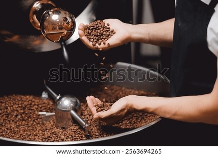 Closeup view of roasted coffee beans in mans hand. Food industry business coffeeshop.