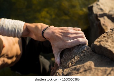 Closeup View Of Rock Climber's Hands Gripping Hold On Natural Cliff. Hand Of A Man Climbing On Granite
