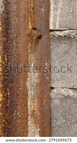 Close-up view of a rough cement wall texture combined with a weathered rusty corrugated metal sheet. The industrial surface features natural wear, corrosion patterns, stains, and aged materials that create a strong urban and industrial character. Ideal for design backgrounds, grunge textures, construction themes, industrial concepts, architectural details, graphic design resources, and creative visual projects