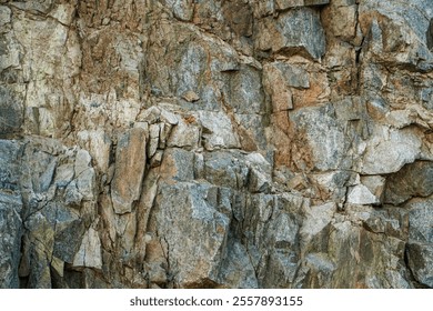 Close-up view of a rough rock face, showcasing varied textures and colors of stone. Natural geological formations. Rough and Rugged Rock Face Texture. - Powered by Shutterstock