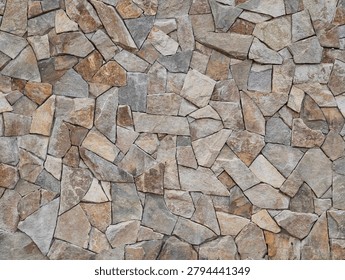 A close-up view of a rough wall built from irregularly shaped stones in a palette of earthy grays, beiges, tans, and browns. The stones create a textured