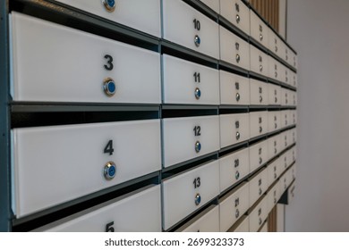 A close-up view of a row of white mailboxes with blue knobs. The mailboxes are organized in a neat, linear arrangement against a neutral background.