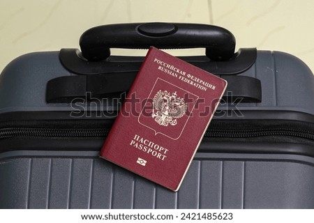 Closeup view of russian passport and grey suitcase.