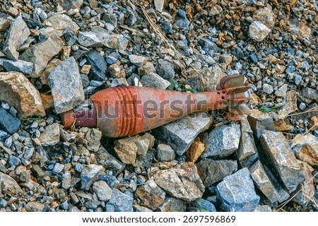 A close-up view of a rusted mortar shell or similar unexploded ordnance