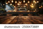 A close-up view of a rustic wooden tabletop with a blurred background of a dimly lit bar interior.