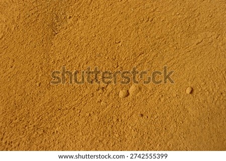 A close-up view of a sandy surface with small bumps and imperfections.