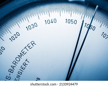 Close-up view of the scale with pointer of an analogue barometer blue toned.