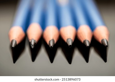 A close-up view of sharpened blue pencils arranged neatly, showcasing their tips, perfect for artistic representation, school projects, and office supplies. - Powered by Shutterstock