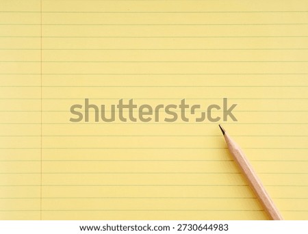 Close-up view of a sharpened pencil resting on a vibrant yellow legal pad, poised for writing notes or capturing ideas