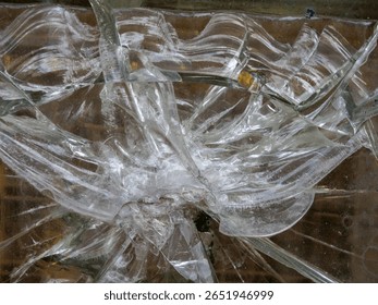 A close-up view of a shattered glass pane reveals intricate crack patterns and sharp edges radiating from an impact point, capturing the tension and beauty in the moment of breakage. - Powered by Shutterstock - Get 15% off with code: PIKWIZARD15