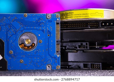 Close-up view showcasing two computer hard drives with visible internal and external components. One hard drive displays its blue circuit board with intricate circuitry paths and electronic parts, whi
