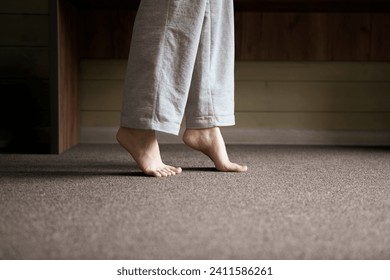 A close-up view shows bare feet standing on a carpeted floor, likely indicating the warmth from a heating system in a residential setting. - Powered by Shutterstock