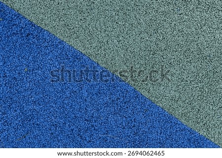 A close-up view shows the texture of a blue and green rubber playground floor.