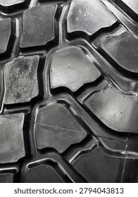 The close-up view shows the tread pattern of a large off-road tire designed for driving on rugged terrains. The grooves and shapes are made for enhanced grip and control.