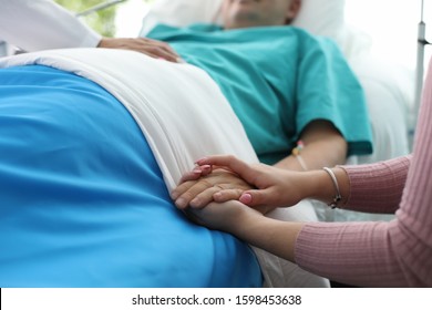 Close-up View Of Sick Person And Family Member Supporting And Wishing Speedy Recovery. Doctor Comfort Patient And His Wife. Intense Treatment At Hospital Concept