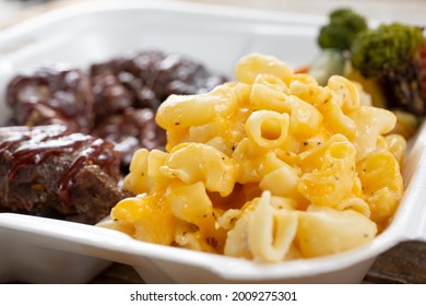 A closeup view of a side of mac 'n cheese, part of a combo of BBQ brisket, in a styrofoam to-go container.