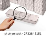 Close-up view of silver bars marked 999.0 purity examined with a magnifying glass. Concept of silver investment, wealth protection, inflation hedge, financial security, precious metals trading, and global economy.