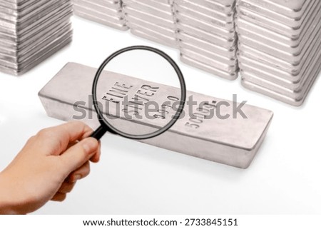 Close-up view of silver bars marked 999.0 purity examined with a magnifying glass. Concept of silver investment, wealth protection, inflation hedge, financial security, precious metals trading, and global economy.
