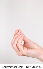 Closeup View Of Single Female Hand Holding Virtual Card Or Invisible Object With Her Fingers Isolated On White Background. Pinch Gesture. Nails Manicured. Vertical Color Photography.