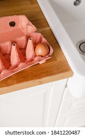 Close-up View Of A Single Raw Chicken Egg In Egg Box On A Kitchen Wooden Counter