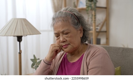 closeup view of sleepy asian old lady propping head while taking an afternoon nap on the sofa in the living room at home. - Shutterstock ID 2255998659