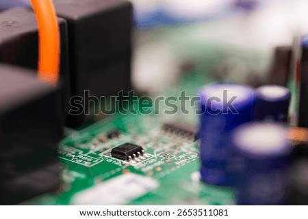 Close-up view of a small microchip and surrounding capacitors mounted on a green printed circuit board, showcasing key components used in electronic devices and automation systems.