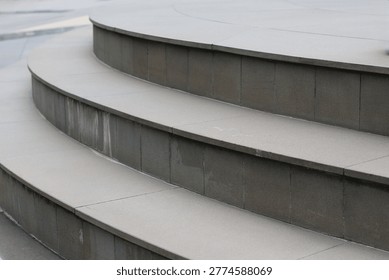 A close-up view of smooth, light-colored stone steps curving gently, accented by darker stone risers