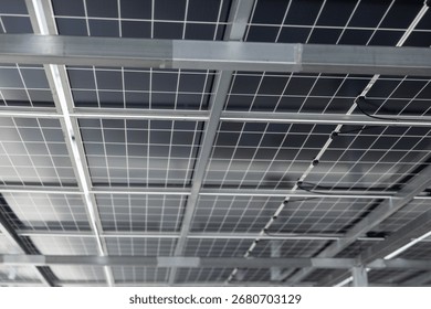 Close-up view of solar panel structure and wiring from underneath. Concept of clean energy, photovoltaic system, renewable power technology, and sustainable infrastructure design.