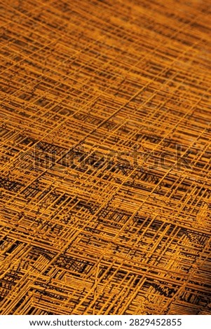 Close-up view of a stacked pile of rusted wire mesh. The rough texture and oxidized colors create a striking industrial aesthetic with strong shadows.