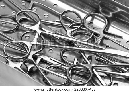 Closeup view of stainless surgical needle drivers lying down on steel sterilization tray for sterilize medical surgery instrument. Selective focus. Set of surgical tools