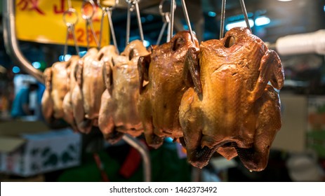Close-up view of a stall vendor with chicken meat hanging in traditional market of Taipei. Stand with fresh chicken sold in a popular marketplace of Taiwan. Sale food for home or restaurants