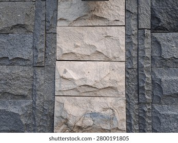A close-up view of a stone wall featuring a combination of dark and light-colored rocks.