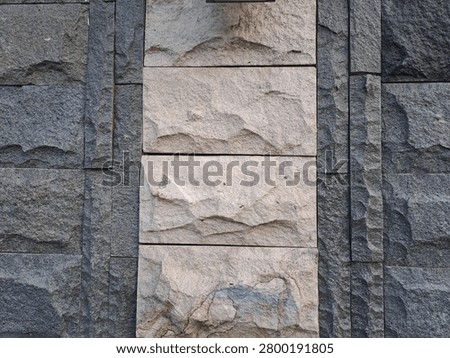 A close-up view of a stone wall featuring a combination of dark and light-colored rocks.