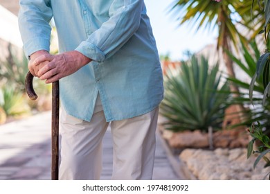 Close-up view of suffering elderly man walking with the help of a cane.