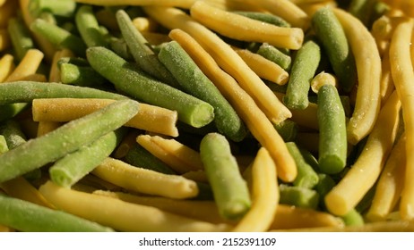 Closeup view of sunny frozen fresh pieces of organic green and yellow stems of beans. Frozen food concept. Abstract organic vegetables background