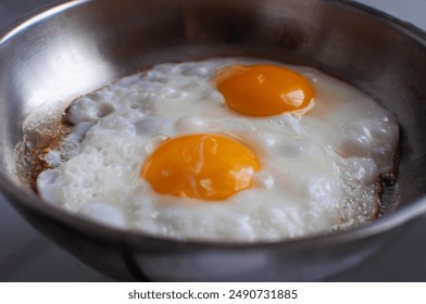 Close-up view of sunny-side up eggs, fried eggs in a stainless steel pan - Powered by Shutterstock