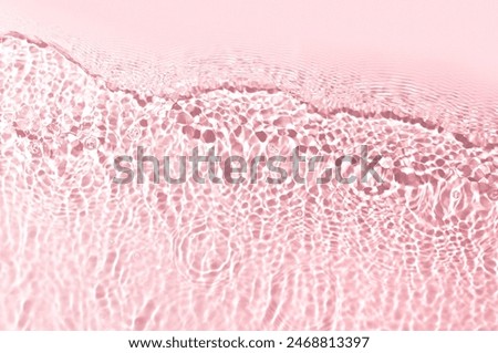 Close-up view of the surface of clear, pink water. Sunlight creates a pattern of ripples and reflections, producing a shimmering, almost crystalline effect.