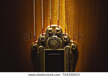 Closeup view of tailpiece of an old dusty gypsy guitar. 