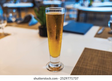 Close-up view of tall glass of beer on restaurant table with blurred background.  - Powered by Shutterstock