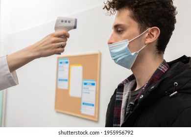 Close-up view. Temperature measurement of a young man in the entrance of a clinic, performed by medical staff in the face of a pandemic - Powered by Shutterstock