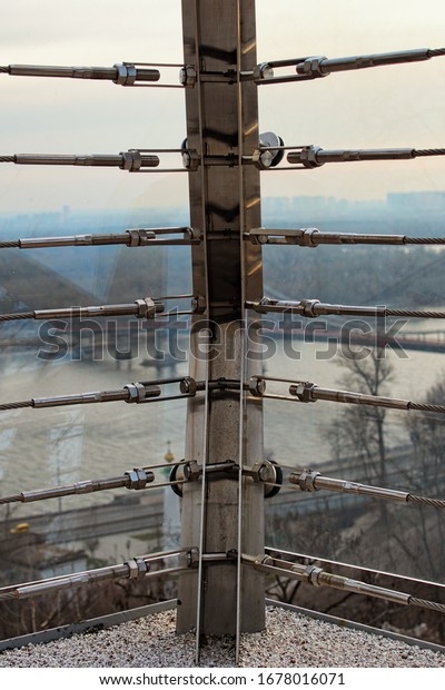 A close-up\
view of tension steel cables with steel fasteners. A detail of the\
railing on the bridge.A geometric pattern. Vertical view. New\
Pedestrian Bridge in Kyiv,\
Ukraine.
