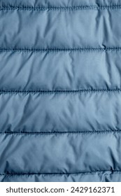 Close-up view of the texture of blue soft puffer down jacket fabric.