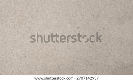 A close-up view of a textured beige surface with natural fiber patterns and subtle imperfections.
