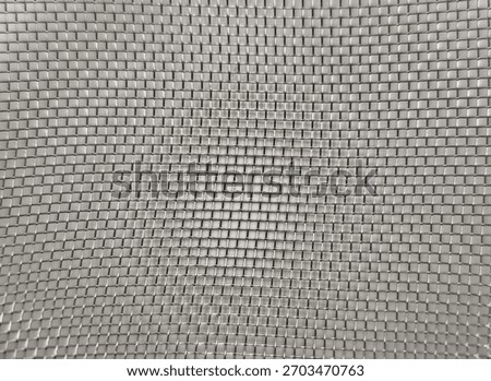 Closeup view textured pattern of a metallic woven mesh grid forming a symmetrical geometric design with reflective silver squares creating a visually hypnotic surface.