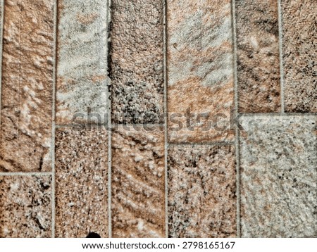 Close-up view of textured sandstone tile flooring in earthy brown and gray tones for interior design. Full frame background texture of rustic ceramic tiles with a vertical natural stone pattern.
