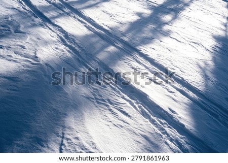 Close-up view of a textured surface with blue and white tones, featuring diagonal lines and dappled shadow patterns.