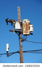 Close-up view of the top of a wooden seaside electricity pylon with some rusty weathered transformer units