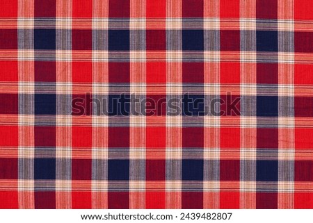 Close-up view of a traditional tartan fabric with a red and blue color scheme showcasing the detailed plaid pattern commonly associated with Scottish kilts