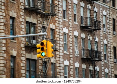 Close-up view of a traffic light and some buildings on background with windows and emergency stairs. Bronx District, New York, USA.